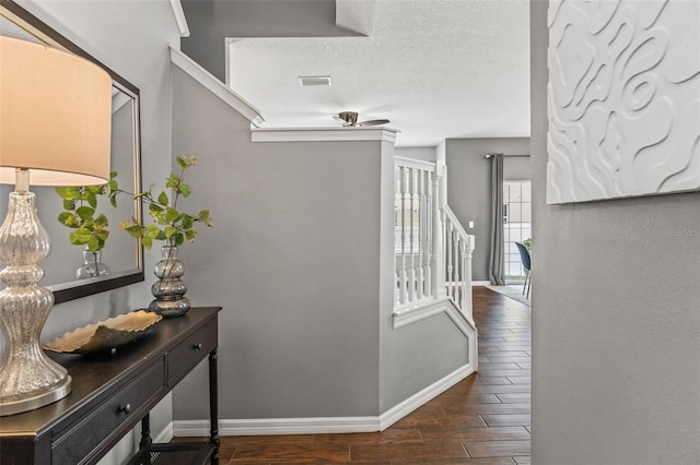 corridor with wood finish floors, visible vents, baseboards, and a textured ceiling