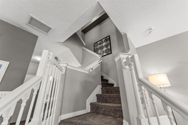 stairs featuring visible vents and a textured ceiling