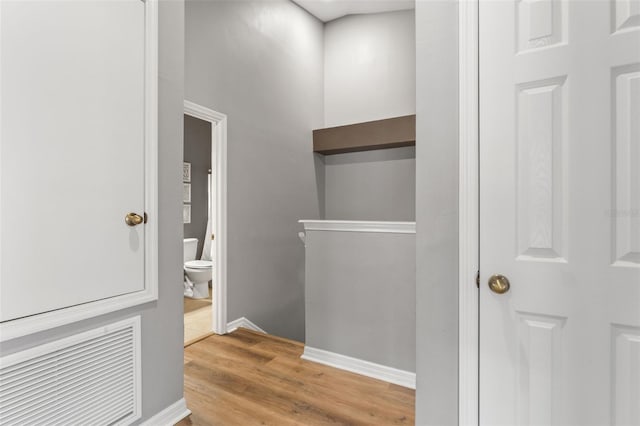 hall with wood finished floors, an upstairs landing, and baseboards