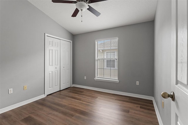 unfurnished bedroom with a ceiling fan, baseboards, dark wood finished floors, vaulted ceiling, and a closet