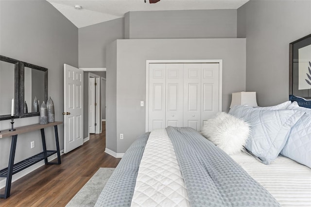 bedroom with a closet, baseboards, high vaulted ceiling, and wood finished floors