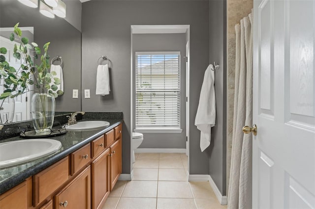 bathroom featuring tile patterned floors, toilet, double vanity, and a sink