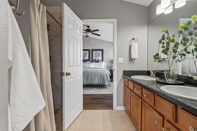 ensuite bathroom with lofted ceiling, ceiling fan, tile patterned flooring, a sink, and connected bathroom