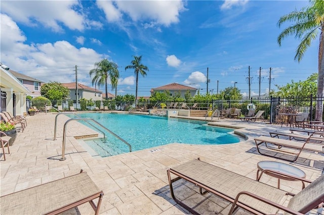 pool with a patio area and fence