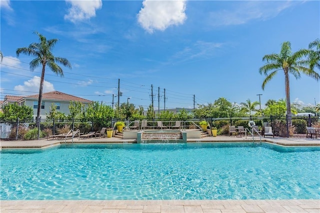 community pool with a patio area and fence