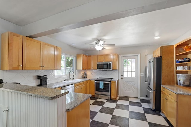 kitchen featuring a sink, backsplash, stainless steel appliances, a peninsula, and dark floors