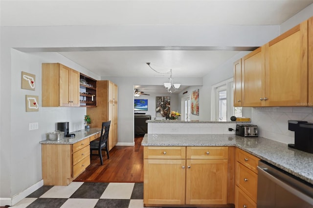 kitchen with backsplash, dark floors, dishwasher, built in desk, and a peninsula