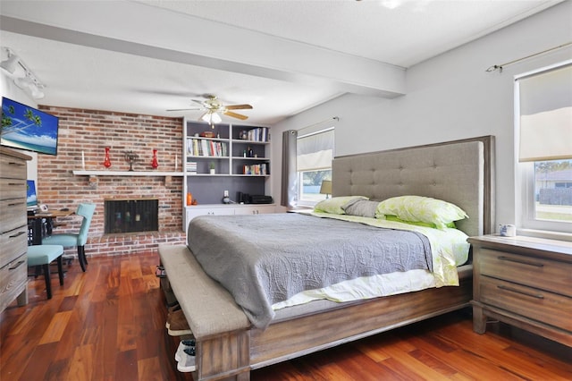 bedroom featuring multiple windows, a brick fireplace, and wood finished floors