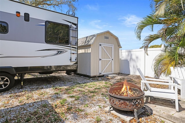 view of shed featuring an outdoor fire pit and fence