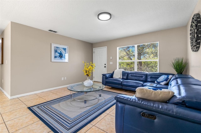 living area with tile patterned floors, visible vents, a textured ceiling, and baseboards