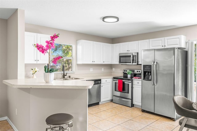 kitchen featuring white cabinets, a peninsula, stainless steel appliances, and a sink