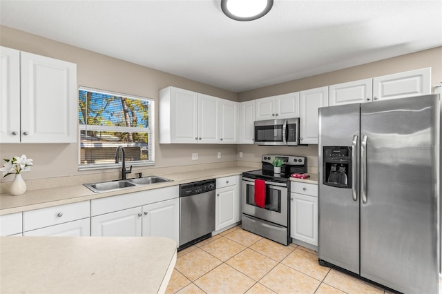 kitchen featuring light countertops, appliances with stainless steel finishes, light tile patterned flooring, white cabinets, and a sink