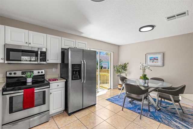 kitchen with visible vents, appliances with stainless steel finishes, white cabinets, light tile patterned flooring, and light countertops