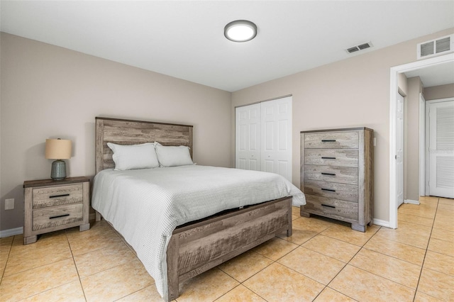 bedroom with light tile patterned floors, visible vents, baseboards, and a closet