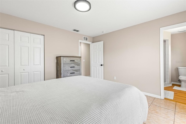 bedroom featuring light tile patterned floors, visible vents, baseboards, and a closet