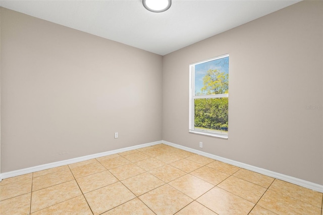 empty room with light tile patterned floors and baseboards