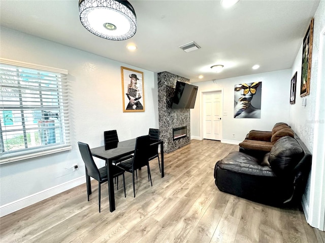 dining space with light wood-type flooring, visible vents, recessed lighting, a large fireplace, and baseboards