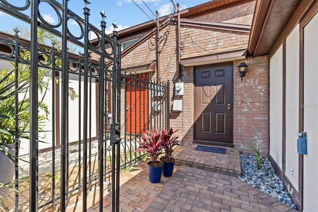 doorway to property featuring brick siding and a gate