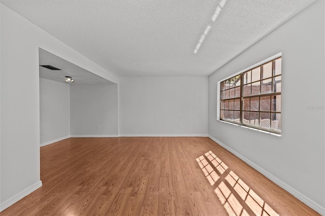 unfurnished room with light wood-style floors, baseboards, and a textured ceiling