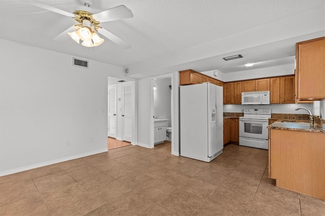 kitchen with white appliances, baseboards, visible vents, and a sink