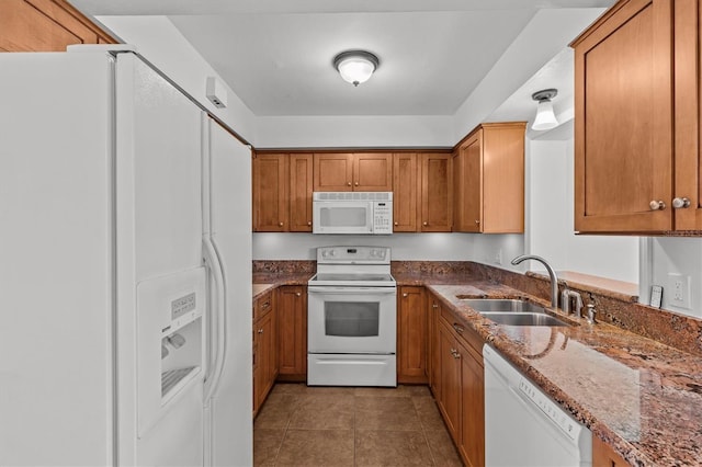 kitchen with brown cabinets, white appliances, and a sink