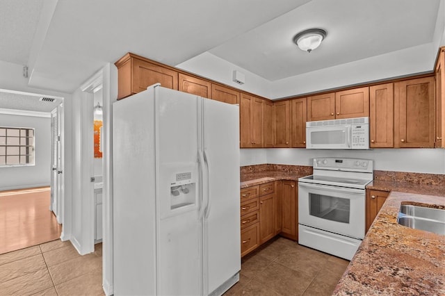 kitchen with visible vents, white appliances, light tile patterned flooring, and brown cabinetry