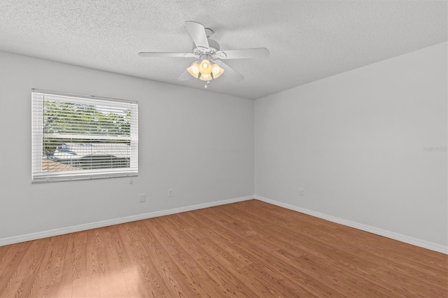 empty room featuring a ceiling fan, wood finished floors, baseboards, and a textured ceiling