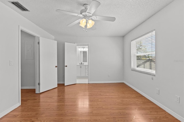 unfurnished room with visible vents, light wood-style flooring, a textured ceiling, and baseboards