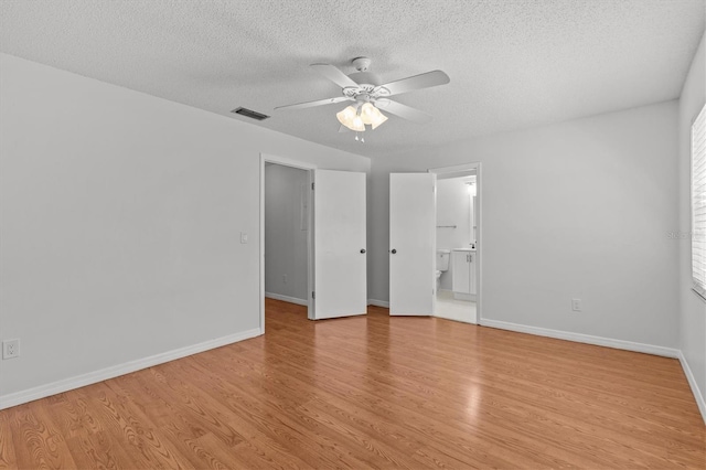 unfurnished bedroom with light wood-style flooring, baseboards, visible vents, and a textured ceiling