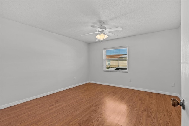 spare room featuring a ceiling fan, wood finished floors, baseboards, and a textured ceiling