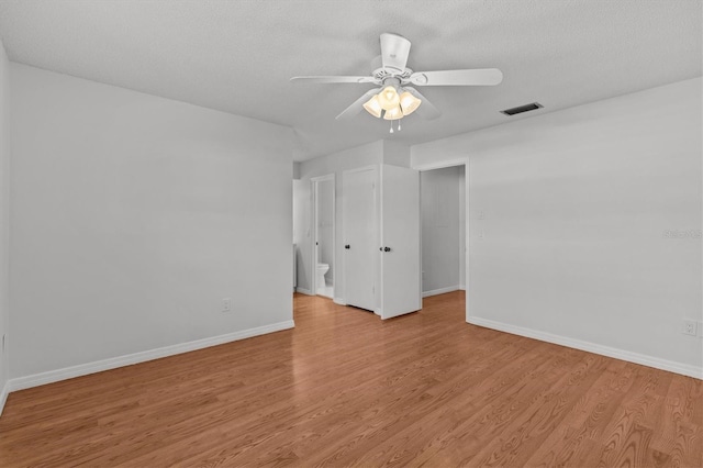 unfurnished room with visible vents, baseboards, wood finished floors, a textured ceiling, and a ceiling fan