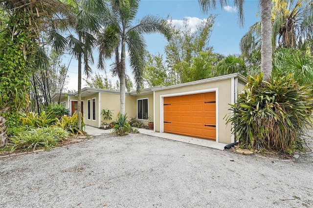 mid-century inspired home with an attached garage, driveway, and stucco siding