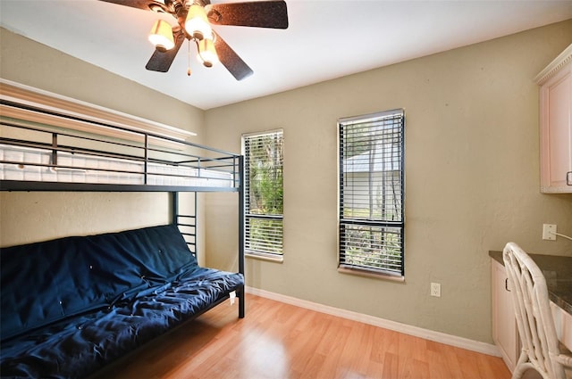 bedroom with light wood-style flooring, a ceiling fan, and baseboards