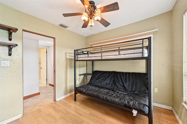 bedroom featuring a ceiling fan, wood finished floors, visible vents, and baseboards