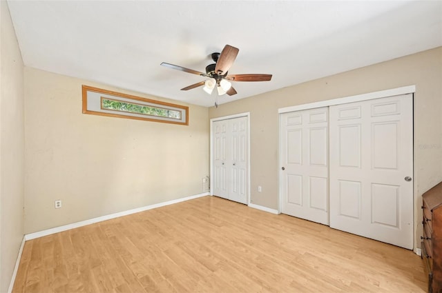 unfurnished bedroom with baseboards, two closets, light wood-style flooring, and a ceiling fan