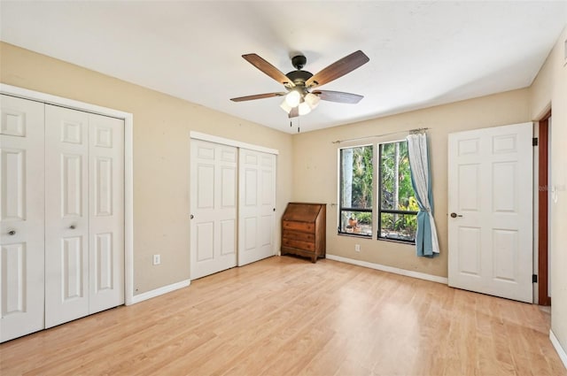 unfurnished bedroom featuring light wood-style flooring, baseboards, multiple closets, and ceiling fan