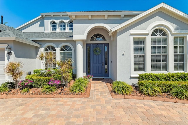 property entrance with stucco siding and an attached garage