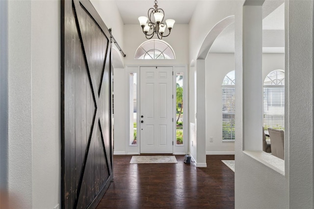 entrance foyer featuring a wealth of natural light, baseboards, dark wood-type flooring, and a barn door