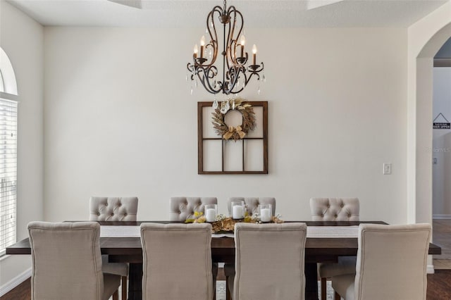 dining room with arched walkways, an inviting chandelier, and baseboards