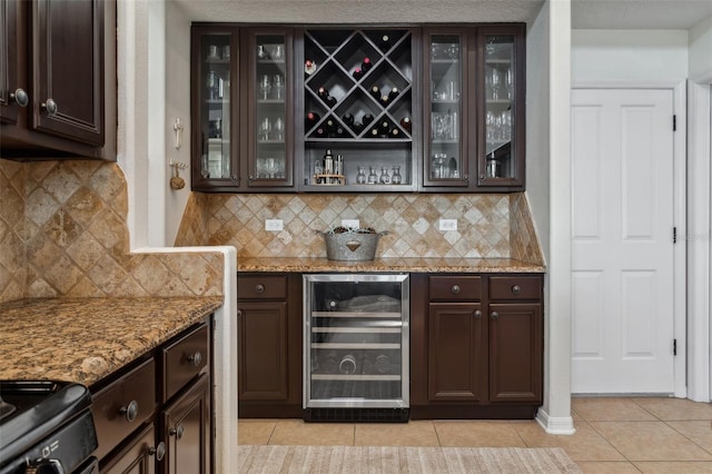 bar with tasteful backsplash, wine cooler, light tile patterned floors, stove, and a bar