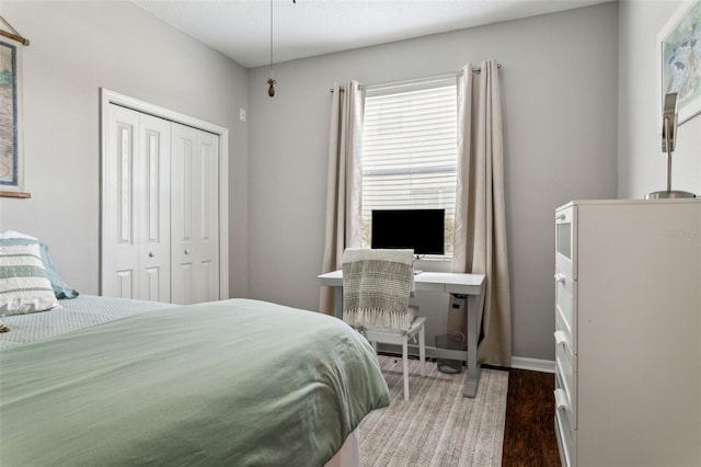 bedroom with wood finished floors, a closet, and baseboards