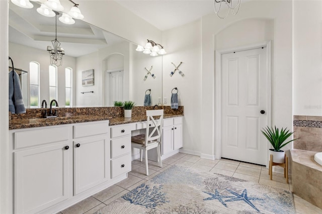 bathroom with a tub, double vanity, an inviting chandelier, tile patterned floors, and a raised ceiling