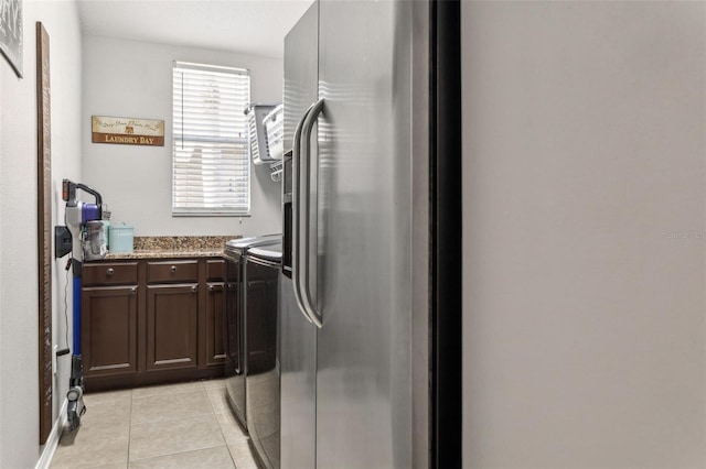 kitchen featuring independent washer and dryer, stone countertops, dark brown cabinetry, stainless steel fridge with ice dispenser, and light tile patterned floors