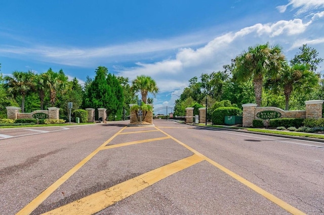 view of street featuring a gated entry, curbs, street lighting, and a gate