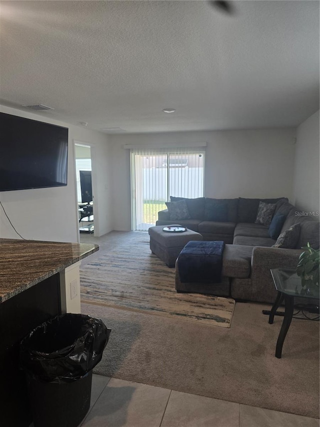 carpeted living room featuring visible vents, a textured ceiling, and tile patterned flooring