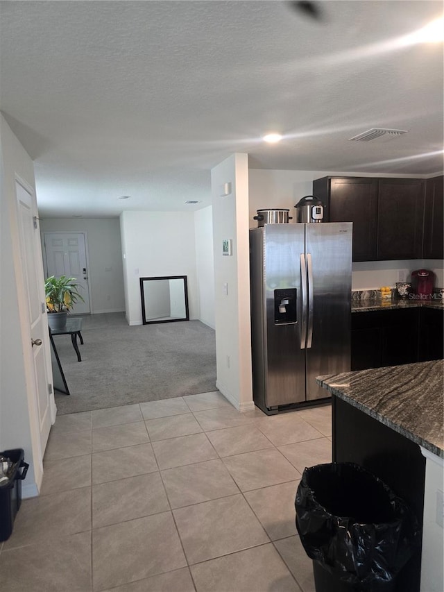 kitchen with visible vents, light carpet, dark stone countertops, light tile patterned flooring, and stainless steel fridge with ice dispenser