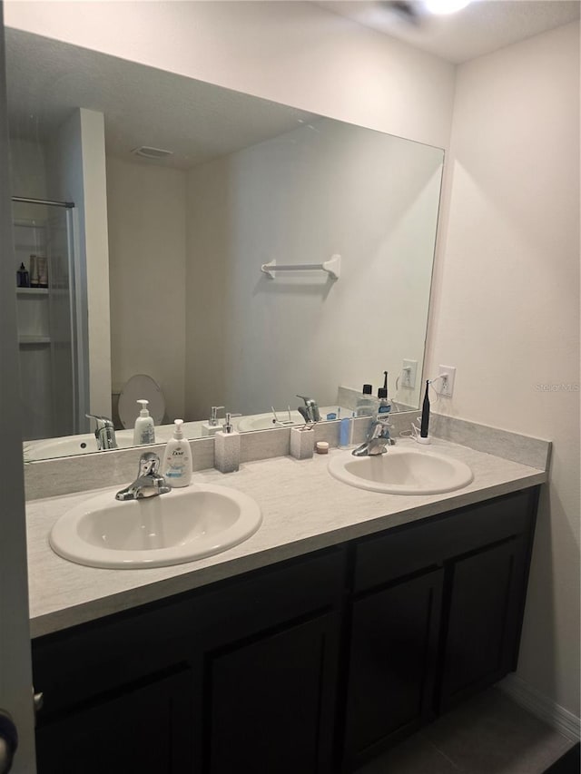 full bath with double vanity, walk in shower, and a sink