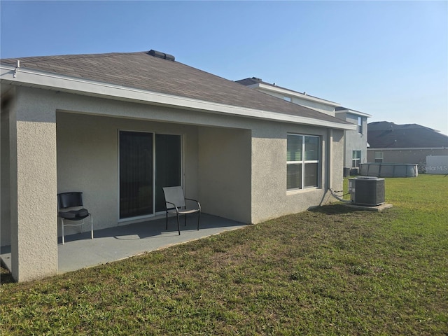 back of property featuring central air condition unit, a lawn, a shingled roof, and stucco siding