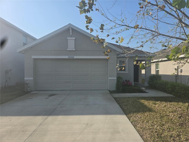 single story home with stucco siding, a garage, and driveway