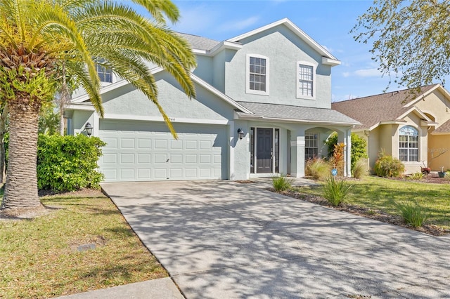 traditional-style house with stucco siding, driveway, a front yard, a shingled roof, and a garage